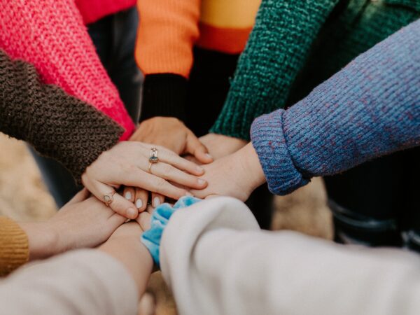 group of friends' hands piled together all wearing warm long sleeves