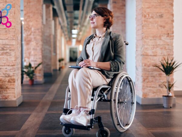 Hire based on ability, not disability. Image of a female worker in a wheelchair in an office.